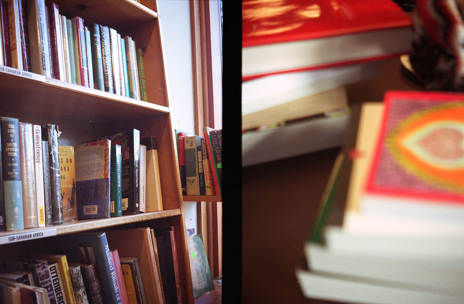 Half-frame photograph of shelves at a bookstore and a stack of books, circa 2007.