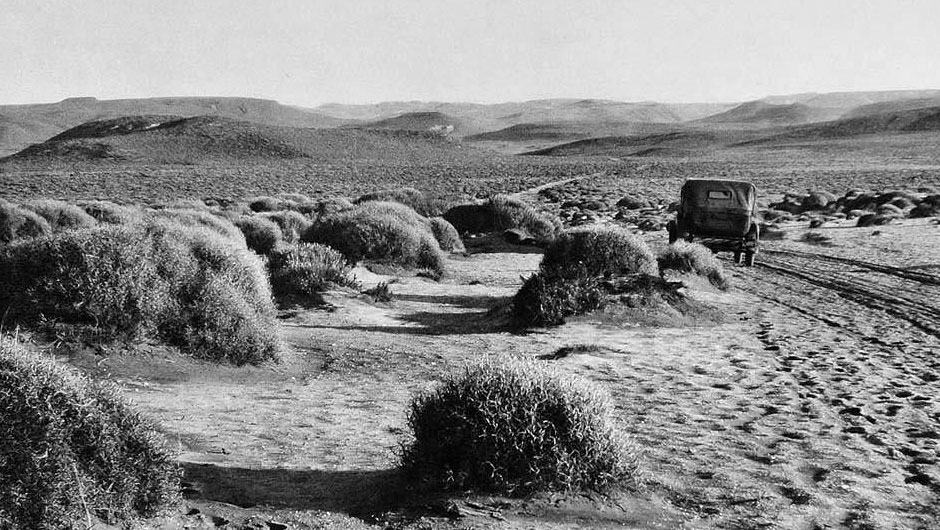 A black and white photograph of a car traversing a desert landscape in Patagonia, ca. 1931