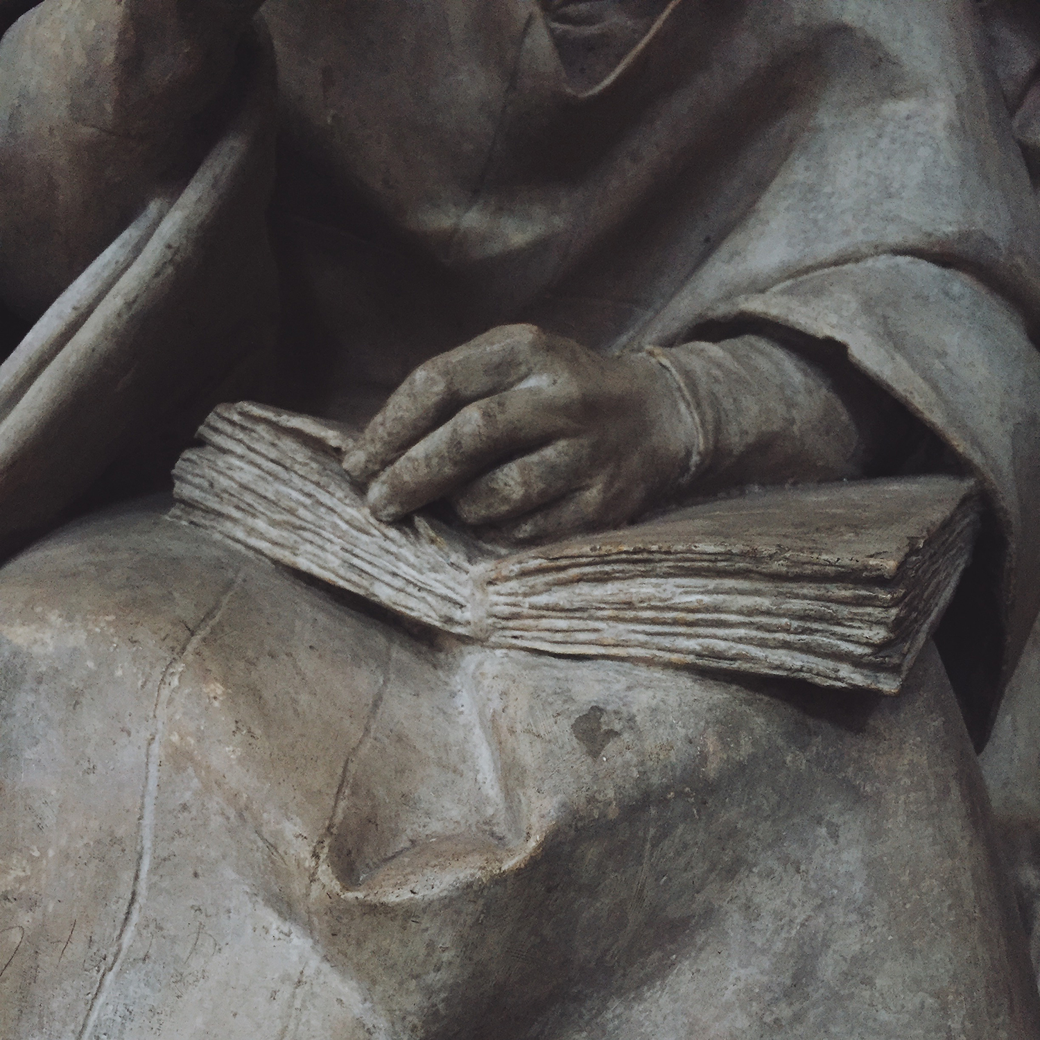 Sculpture of a book in the lap of probably a saint, but it's not quite clear